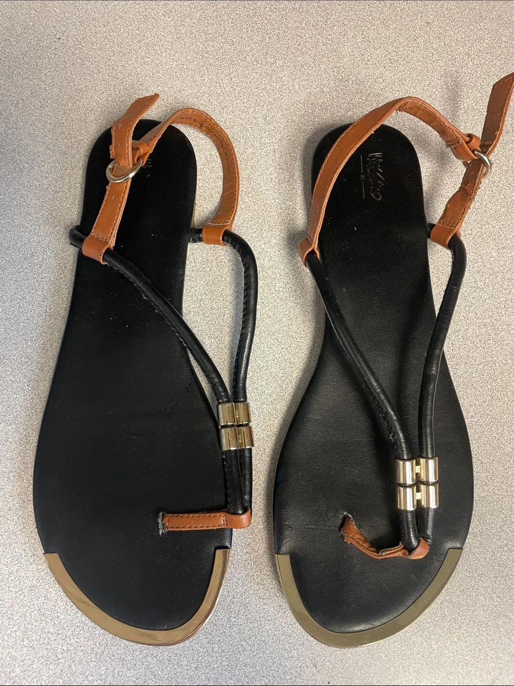Black and brown t-strap sandals with gold accents